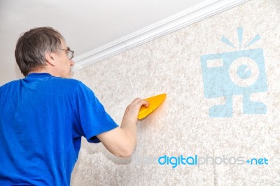 Man Smoothing The Wallpaper With A Spatula Stock Photo