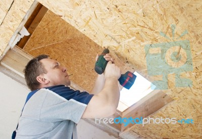 Man Worker Twists The Screw Into The Ceiling With A Screwdriver Stock Photo