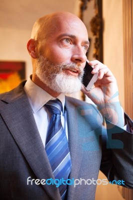 Middle-aged Businessman Listening On Smartphone At Home Stock Photo