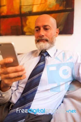 Middle-aged Businessman Listening On Smartphone At Home Stock Photo