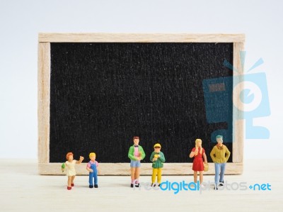 Miniature Children Standing In Front Of A Blackboard On Wooden B… Stock Photo