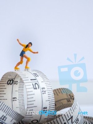 Miniature Woman Skating On Measuring Tape, Thinking Of Weight Lo… Stock Photo