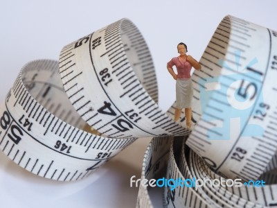 Miniature Woman Standing Near Measuring Tape, Thinking Of Weight… Stock Photo