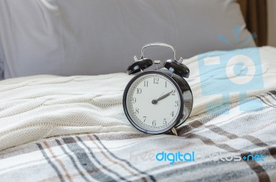 Modern Black Alarm Clock On Bed In Bedroom Stock Photo