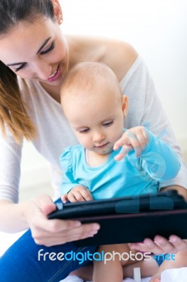 Mother And Baby Girl Using Digital Tablet At Home Stock Photo