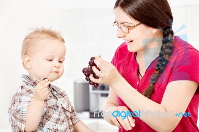 Mother Feeding Child With Grape Stock Photo