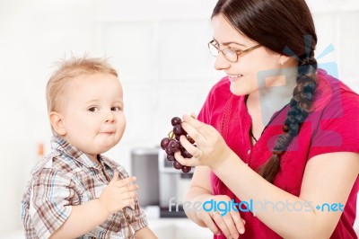 Mother Feeding Child With Grape Stock Photo