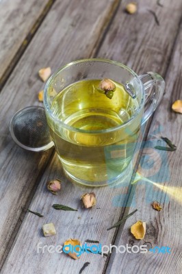 Mug Of Flavored Green Tea With Rose Buds And Petals Stock Photo