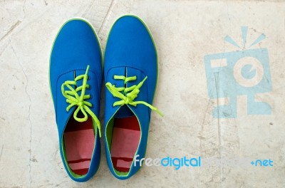 New Blue Sneaker On Textured Cement Floor Stock Photo