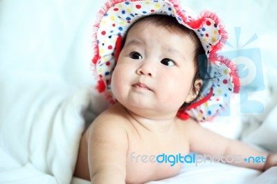 Newborn Baby With Colorful Floppy Hat Lying Down On A White Blan… Stock Photo