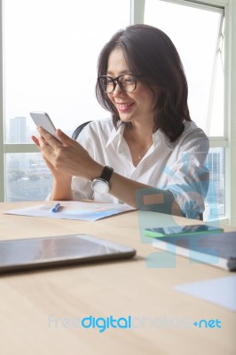 Office Table Scene Of Asian Working Woman Reading Message On Mobile Phone For Modern Life Connecting Stock Photo