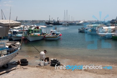 Old Man Preparing To Fish From The Beach At Paphos Cyprus Stock Photo