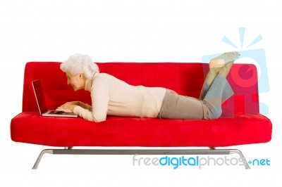 Old Woman With Laptop On Sofa Stock Photo