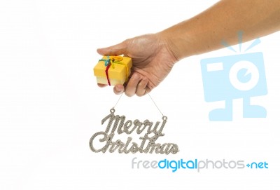 One Hand Holding Yellow Gift Box And Merry Christmas Sign Stock Photo