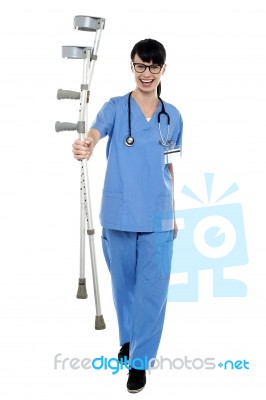 Orthopedic Doctor Walking Towards Camera With Crutches In Hand Stock Photo