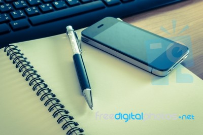 Pen And Cell Phone On A Notebook With Keyboard Stock Photo