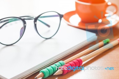 Pencils And Eyeglasses On Open Blank White Notebook With Coffee Stock Photo