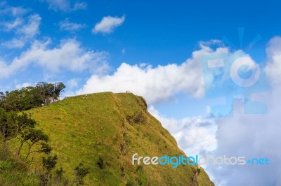 People Hiking To Top Of Mountain With Blue Sky Stock Photo
