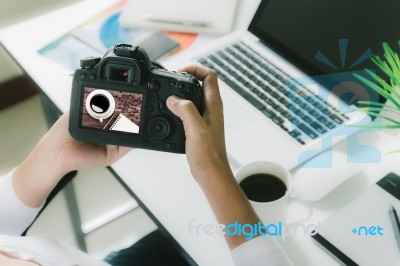 Photographer Holding Camera Checking Photo On Her Desk Workspace… Stock Photo