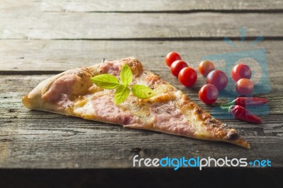 Piece Cut Of Pizza On Table, Cherry Tomato And Hot Peppers Stock Photo