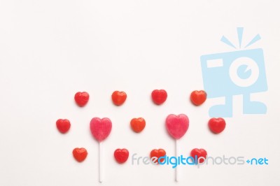 Pink Valentine's Day Heart Shape Lollipop With Small Red Candy In Cute Pattern On Empty White Paper Background. Love Concept. Colorful Hipster Style. Knolling Top View Stock Photo