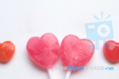 Pink Valentine's Day Heart Shape Lollipop With Small Red Candy In Cute Pattern On Empty White Paper Background. Love Concept. Colorful Hipster Style. Knolling Top View Stock Photo