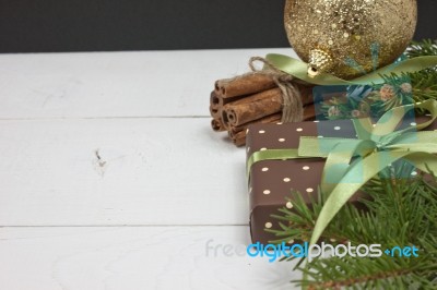 Polka Dot Gift With Christmas Decoration With Cinnamon And Pine Branches On White Wood Background Stock Photo