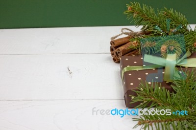 Polka Dot Gift With Christmas Decoration With Cinnamon And Pine Branches On White Wood Background Stock Photo