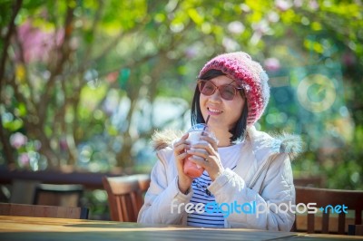 Portrait Of 40s Years Asian Woman With Cool Juicy Drinking Bottle In Hand With Happiness Emotion Sitting In Beautiful Park Background Stock Photo