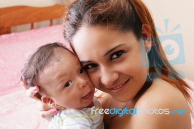 Portrait Of A Hispanic Happy Young Mother Holding A Baby Stock Photo