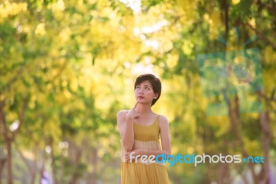 Portrait Of Beautiful Young Asian Woman Thinking Against Yellow Stock Photo