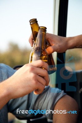 Portrait Of Two Friends Toasting With Bottles Of Beer In Car Stock Photo