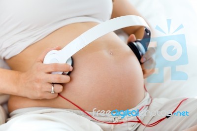 Pregnant Woman Putting Headphones On Her Belly Stock Photo