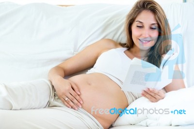 Pregnant Woman Reading A Book On Sofa Stock Photo