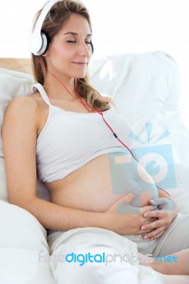 Pregnant Woman Sitting On Sofa At Home And Listening Music In He… Stock Photo