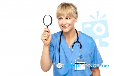Pretty Physician Looking Through Magnifying Glass Stock Photo