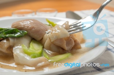 Rad Na, Famous Thai Chinese Style Wide Rice Noodle Dish With Tasty Tender Pork With Thick Gravy Sauce. Close Up With Fork Stock Photo