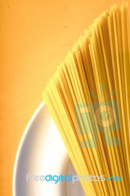 Raw Spaghetti  On The White Plate On The Yellow Background Vertical Stock Photo