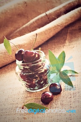 Red Cherries In Glass Jar On Sackcloth Stock Photo