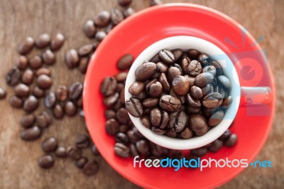 Red Coffee Cup With Coffee Beans On Wooden Table Stock Photo