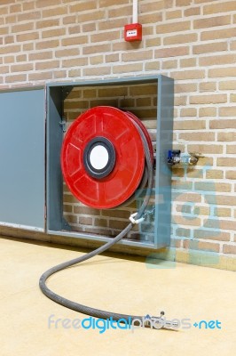 Red Fire Hose On Reel At Wall Stock Photo