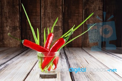 Red Hot Chilli Peppers And Green Onions In Glass Of Water Stock Photo