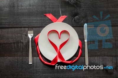 Red Ribbon In Heart Shape On Plate And Wooden Background Stock Photo