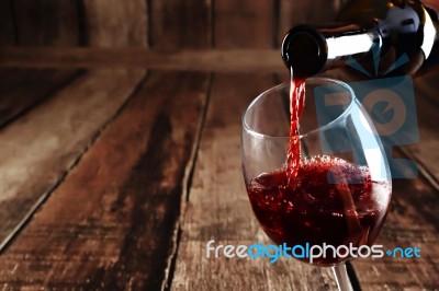 Red Wine Is Poured From Bottle To Glass Stock Photo
