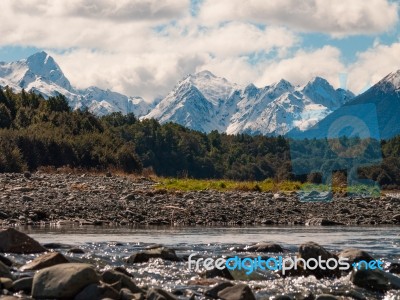 River Flowing With A Snowy Mountain Scape In The Background Stock Photo