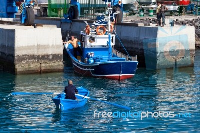 Rowing Fishing Boat To Side Of Harbour Stock Photo