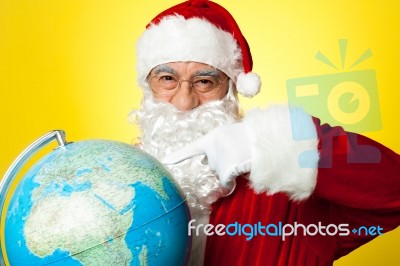 Santa Claus Selecting Location  On Globe Stock Photo