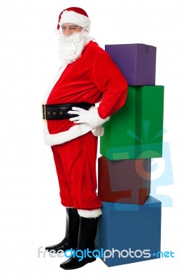 Santa Leaning Over Colorful Pile Of Xmas Presents Stock Photo