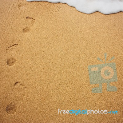 Sea Wave With Foam And Human Footprints On Sand Stock Photo