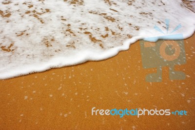 Sea Wave With Foam On Sand Stock Photo